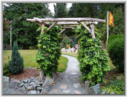 The backyard archway leads to a landscaped basketball court, Sequoia cabin, Cedar swing and Miami river